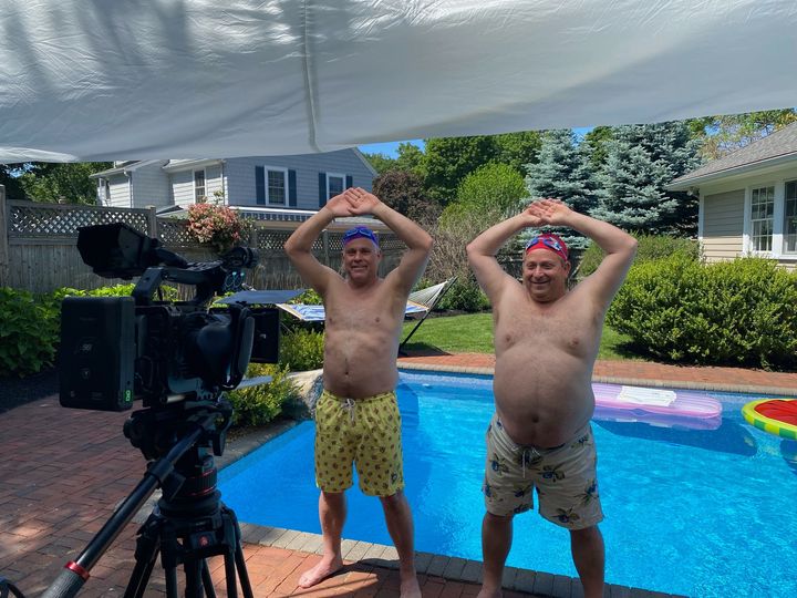 two men in swim trunks by a pool